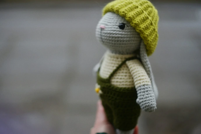 Crocheted bunny wearing overalls and a hat.
